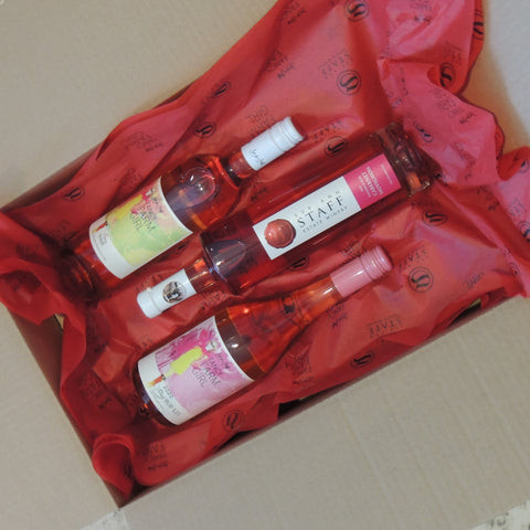 Packaged bottles of rosé on tissue paper in a cardboard wine shipping box.
