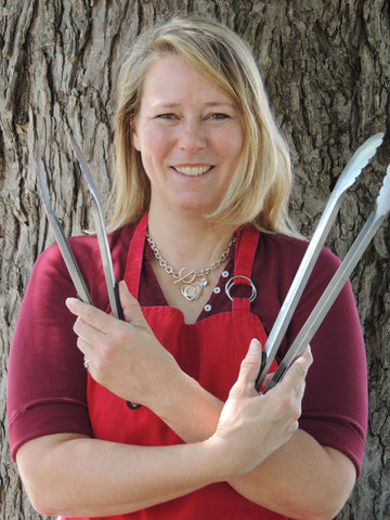 Photo of Sue-Ann Staff holding bbq tongs and smiling!