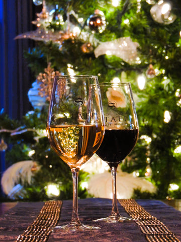 Glasses of wine in front of a fully decorated Christmas tree