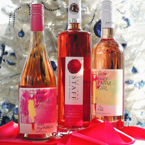 Three bottles of wine from Susan's Estate Winery on a decorative tray with a festive background.