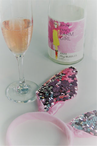 a glass of Fancy Farm Girl Flirty Bubbles with an empty bottle and pink sequinned bunny ears for Easter brunch