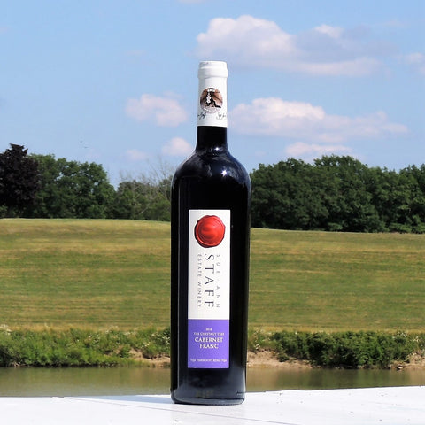 photo of a bottle of 2018 Chestnut Tree Cabernet Franc taken outside, with a view of the pond behind. 